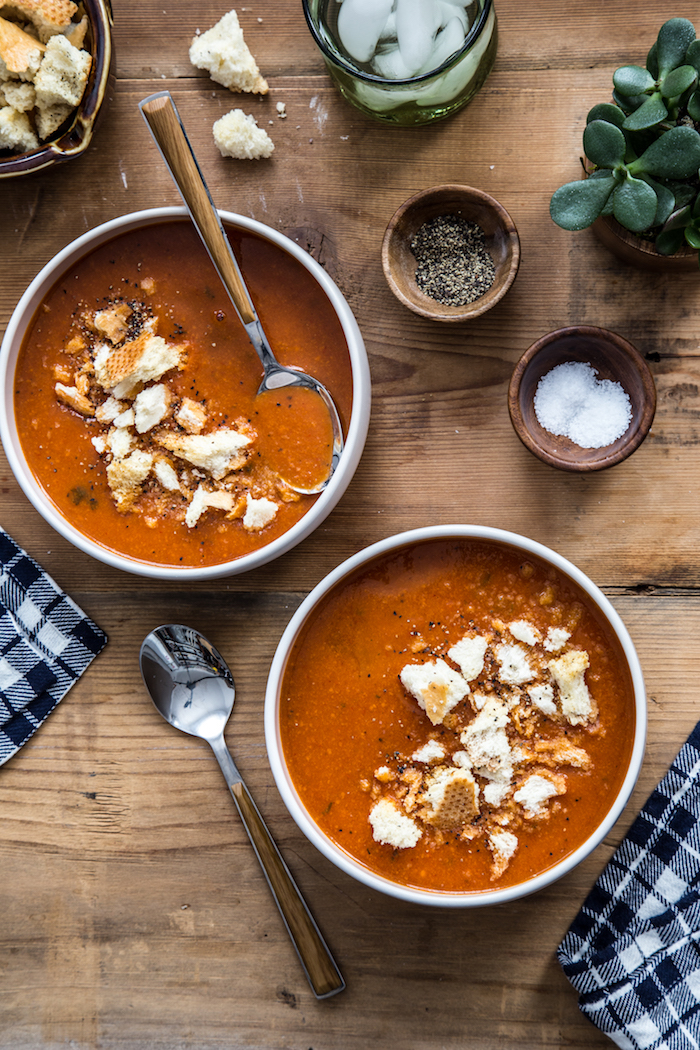 old fashioned potato soup, two bowls full of soup with croutons, small wooden bowls full of spices on wooden table