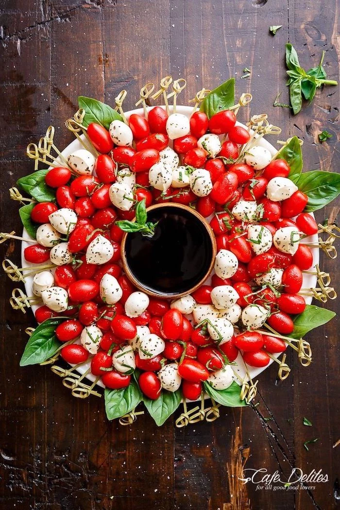cherry tomatoes and baby mozzarella, basil leaves arranged as a wreath, easy christmas appetizers finger foods, bowl in the middle
