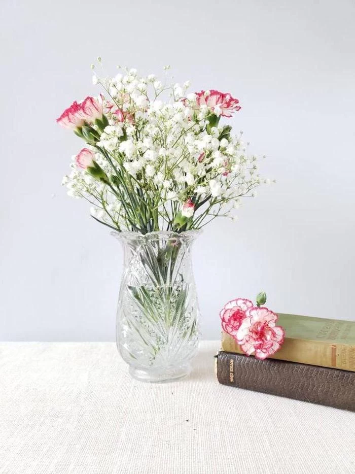crystal vase with flowers inside, placed on wooden table, what to get your mom for christmas, two books on the side