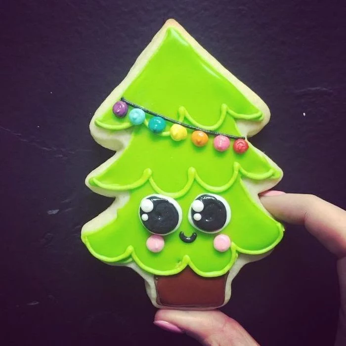 christmas tree shaped cookie, how to decorate sugar cookies, decorated with green and brown icing, placed on black surface