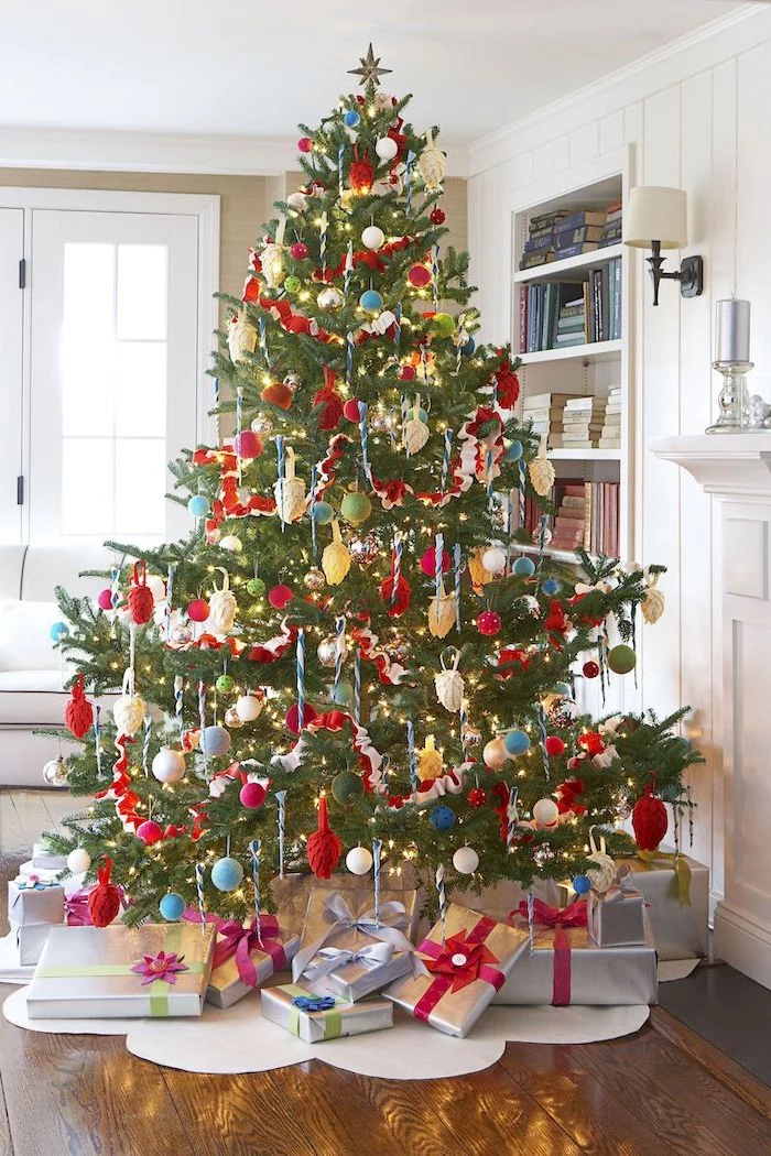 colorful christmas tree, decorated with red blue and green ornaments, wrapped presents underneath, place on white rug