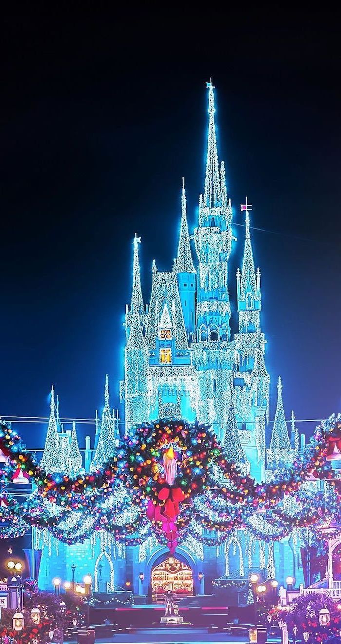 Disney castle covered with lights, free desktop wallpaper, lights garlands and wreaths over a pathway, leading to the castle