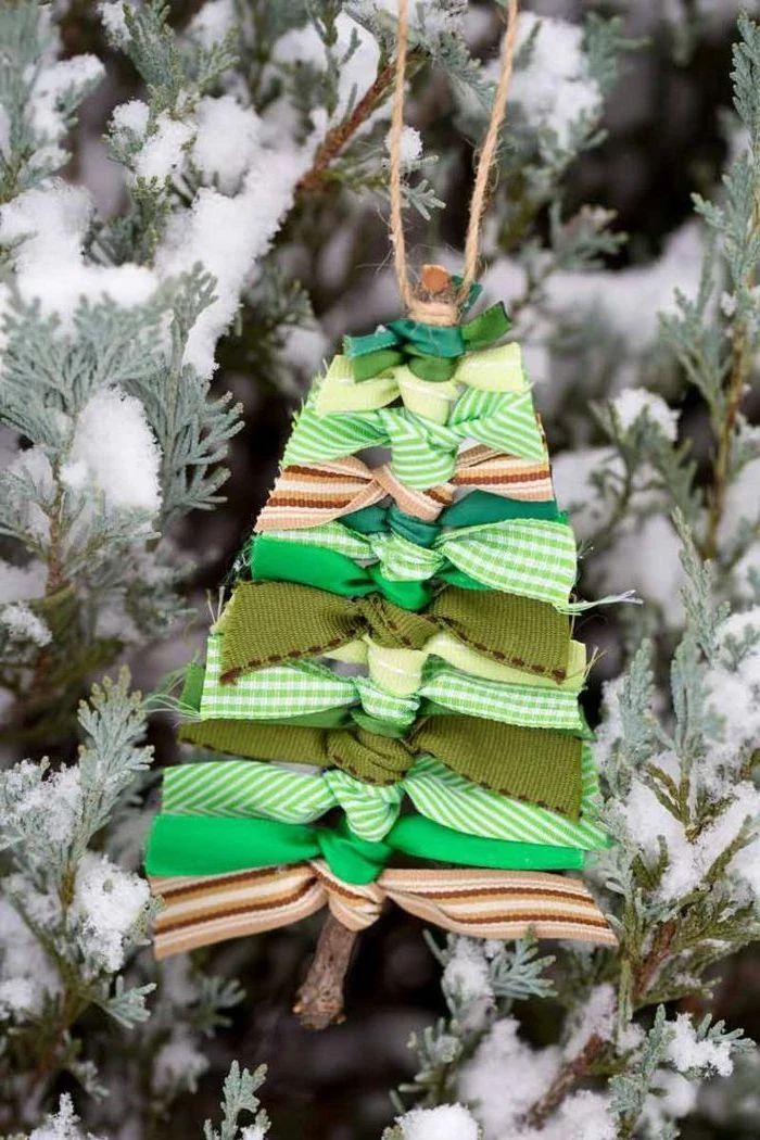 christmas arts and crafts, christmas tree ornament, made with a twig and ribbons with different patterns, hanging on a tree