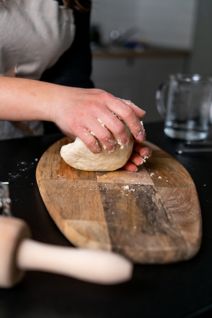 dough on wooden cutting board, naan bread, placed on black surface