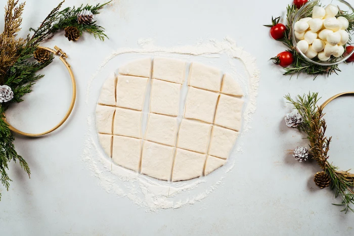 rolled out dough, cut into squares, pull apart christmas bread, placed on lightly floured white surface
