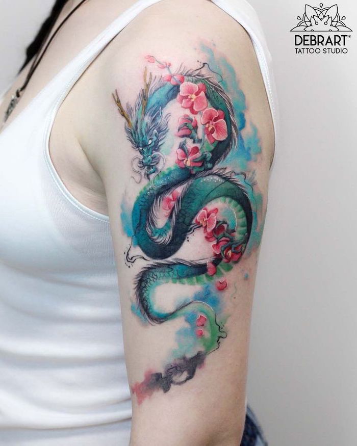 watercolor dragon tattoo with pink blossoming flowers, shoulder tattoo, red dragon tattoo, woman wearing white top