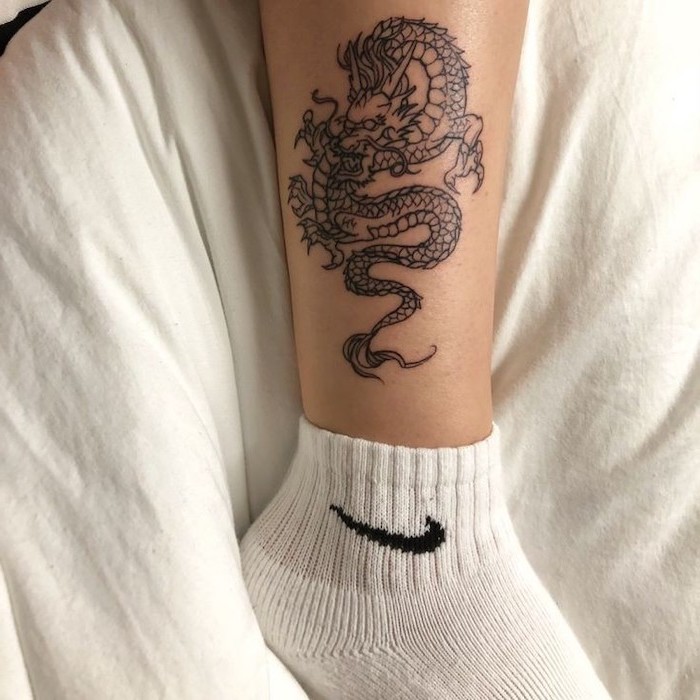 ankle tattoo, woman wearing white socks, white bed linen, small dragon tattoos