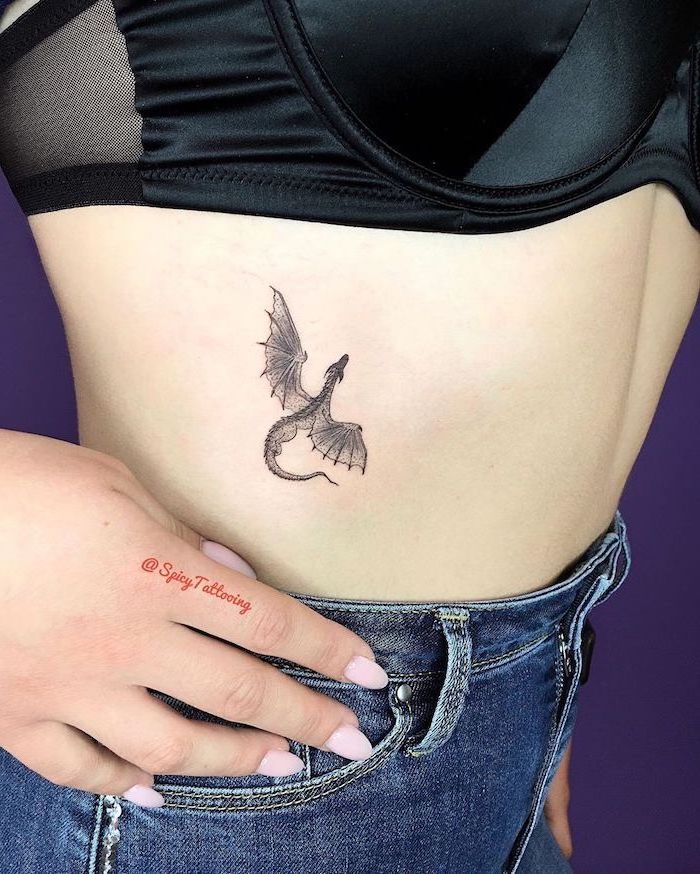 woman wearing jeans and black velvet top, chinese dragon tattoo, flying dragon rib cage tattoo