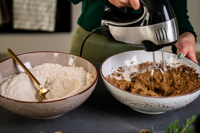 wet and dry ingredients in two separate bowls, being whisked together, vegan gingerbread cookies, placed on grey surface