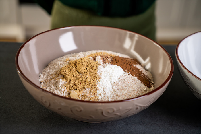 decorating gingerbread cookies, dry ingredients, mixed in a ceramic bowl, placed on black surface