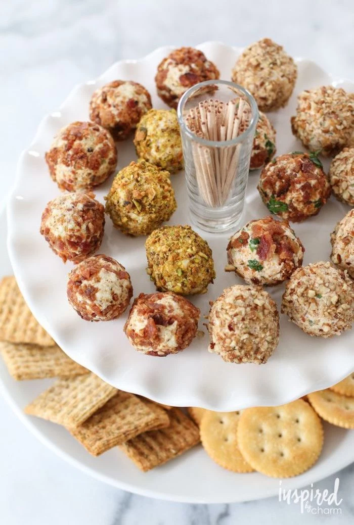 cheese truffles covered with different garnishes, finger foods for party, arranged around a small glass with toothpicks