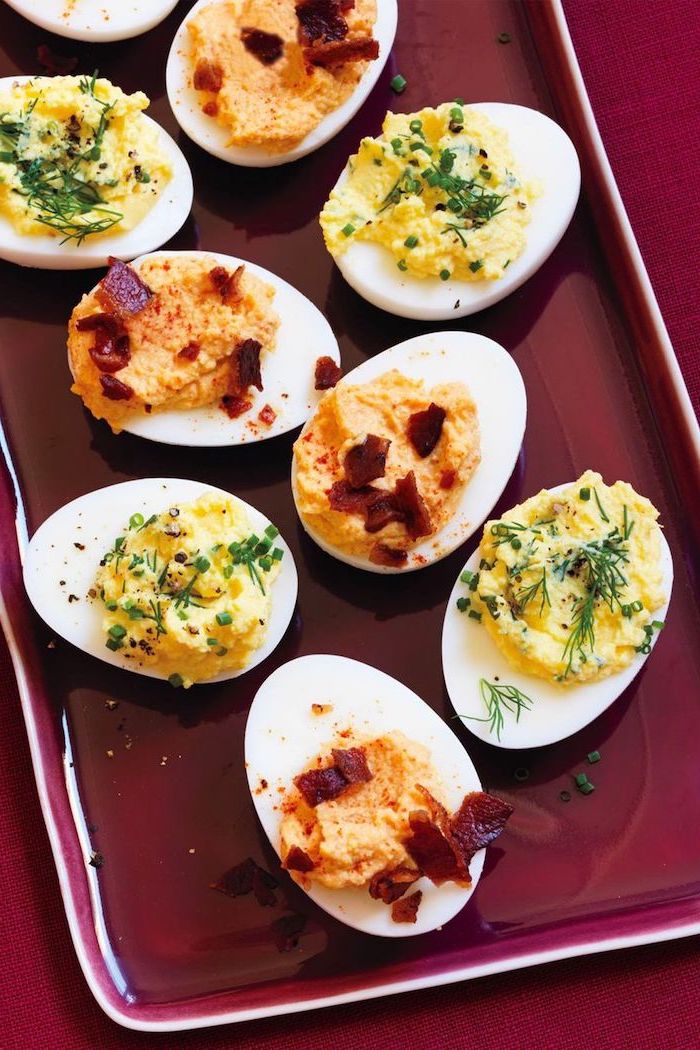 deviled eggs, christmas appetizer recipes, halved boiled eggs, filled with different dips, arranged on red plate