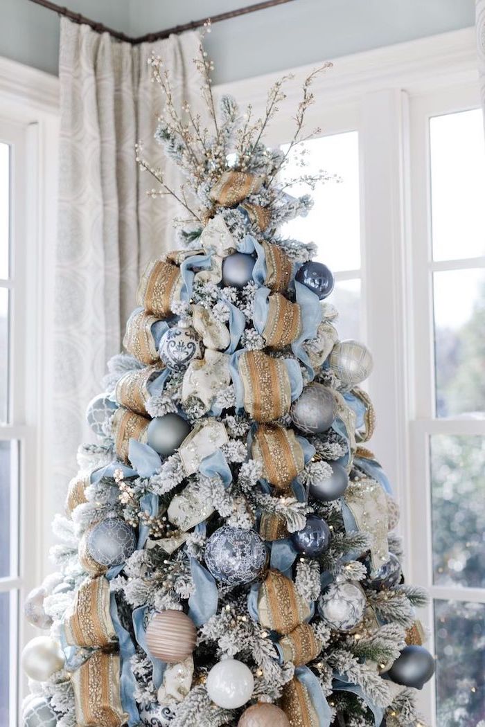 tree with faux snow, decorated with blue and gold ribbons, colorful christmas tree, blue and silver ornaments