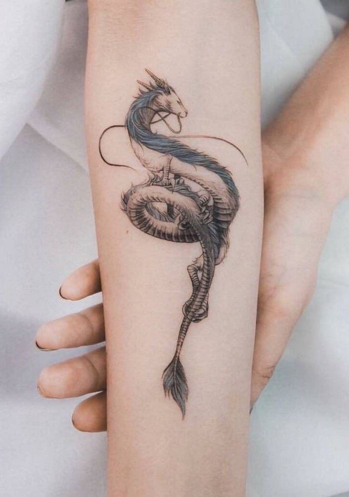 forearm tattoo, dragon arm tattoo, blue dragon, hands leaning on white bed linen