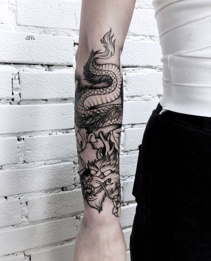 white brick wall, woman wearing white top and black skirt, large dragon forearm tattoo, dragon tattoo meaning