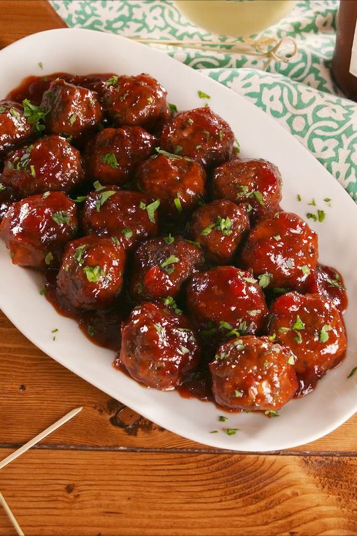 glazed meatballs in white plate, christmas party finger foods, placed on wooden surface, next to turquoise cloth
