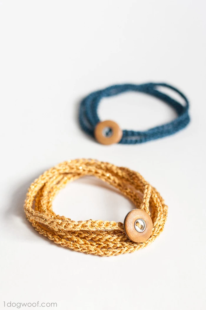 two crochet bracelets in gold and blue, gift ideas for men, with brown leather buttons, placed on white surface, step by step diy tutorial