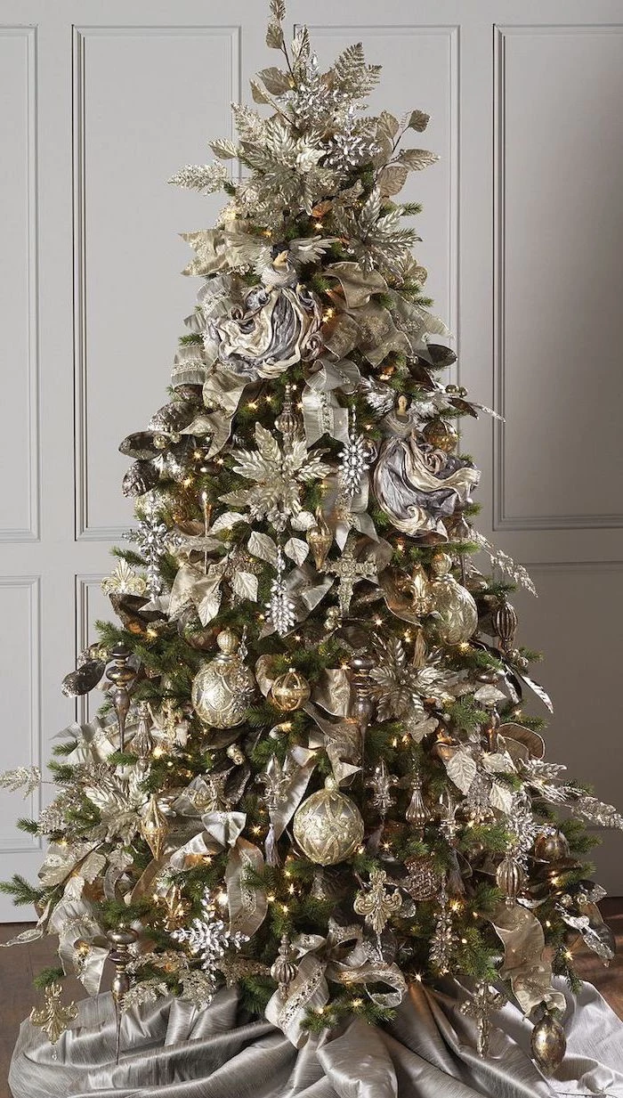 tree placed on grey silk rug, decorated with gold and silver ornaments, colorful christmas tree, faux flowers