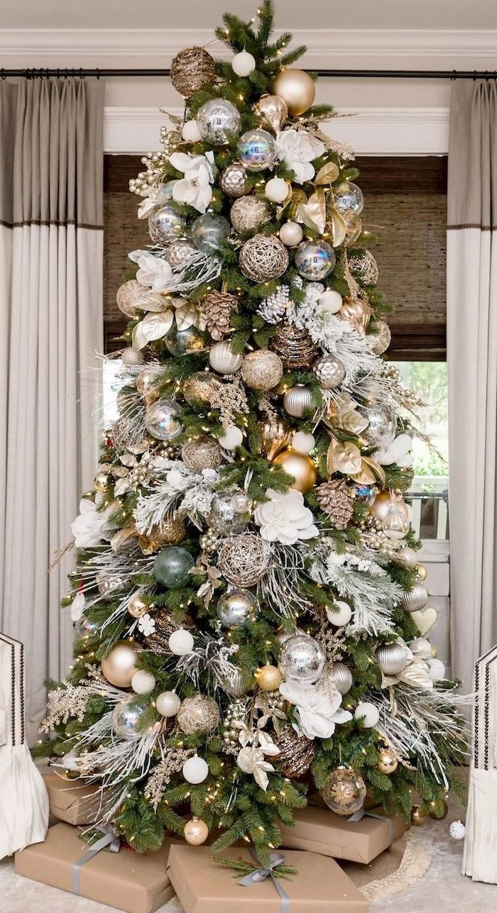 wrapped presents underneath a tree, decorated with gold and blue ornaments, rose gold christmas tree, white faux flowers
