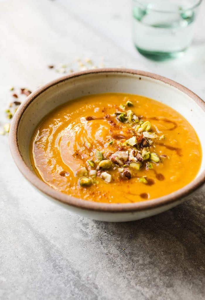 white ceramic bowl full of soup, pistachio nuts on top for garnish, old fashioned potato soup, granite countertop