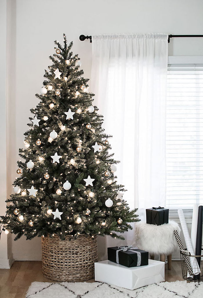 tree decorated with lights, white ornaments and stars, beautiful christmas trees, inside a basket on wooden floor