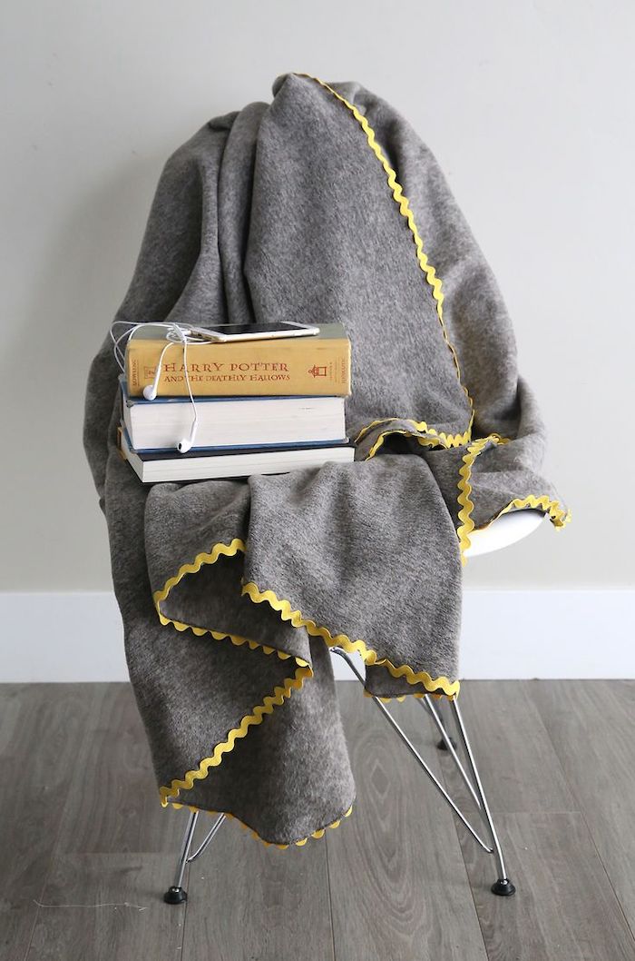 grey fleece blanket spread out on a chair, christmas presents for moms, three books and a phone on top of it