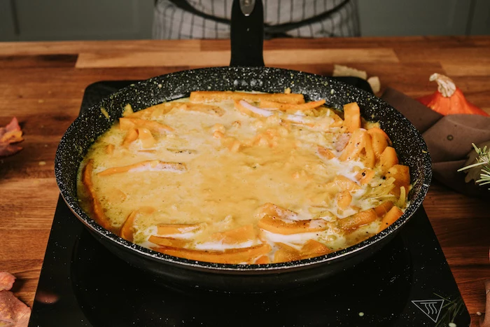 sliced pumpkin, milk poured on top of it, cooking in a black skillet, potato soup recipe, wooden table