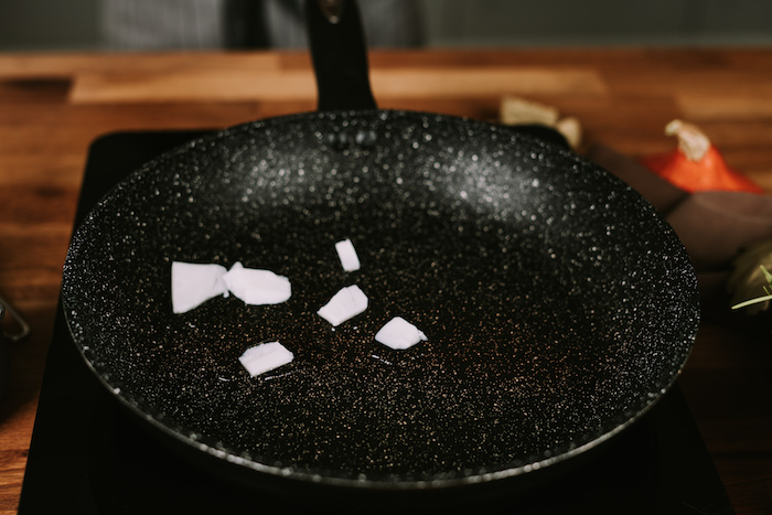 coconut butter, melted in a black skillet, placed on a hot plate, creamy soup recipes, blurred background