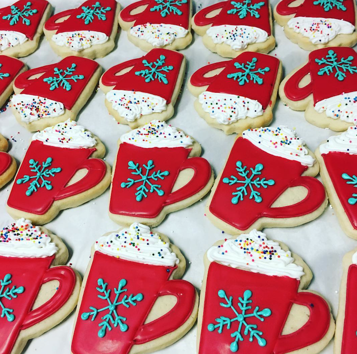 cookies in the shape of hot chocolate mugs with cream on top, royal icing for decorating cookies, decorated with white red and blue icing