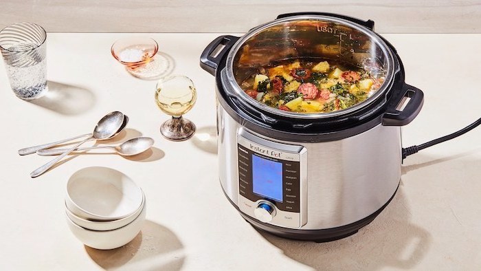 soup cooking in an instant pot, placed on white table, christmas gifts for mothers, two white bowls and spoons on the side