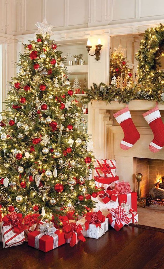 tree decorated with red and gold ornaments, standing next to the fireplace, presents underneath, decorating christmas tree with ribbon