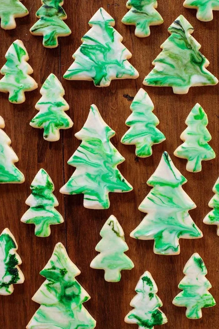 christmas tree shapes cookies, placed on wooden surface, christmas cookie decorating ideas, white and green icing on top