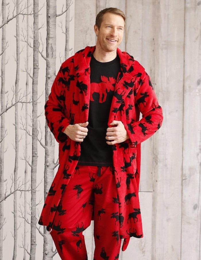 blonde man smiling, wearing red and blue set of pyjamas and cozy robe, unique gifts for men, lots of stags on the clothes
