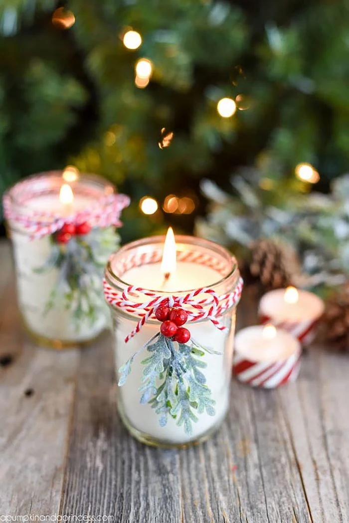 mason jars with candles inside, decorated with mistletoe branches and cranberries, what to get mom for christmas\