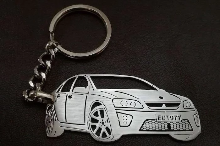 metal keyring, personalised with the owner's car and plate number, unique gifts for men, placed on black leather surface