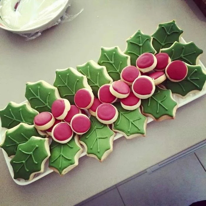 mistletoe shaped cookies, arranged on white plate, royal icing for decorating cookies, decorated with red and green icing