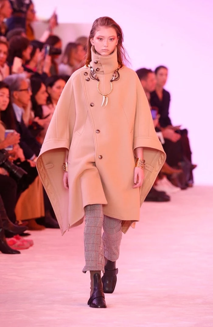 clothing trends, model walking down the runway, wearing plaid trousers and long beige coat, black boots