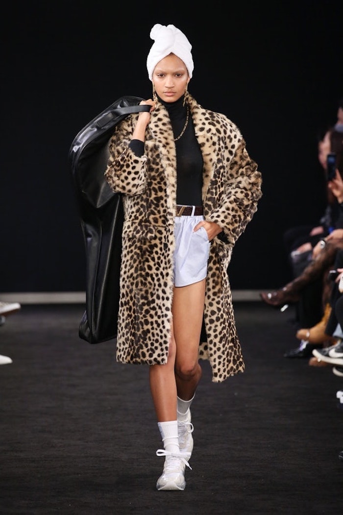 model walking down the runway, wearing silk white shorts and black blouse, clothing trends, furry leopard print coat