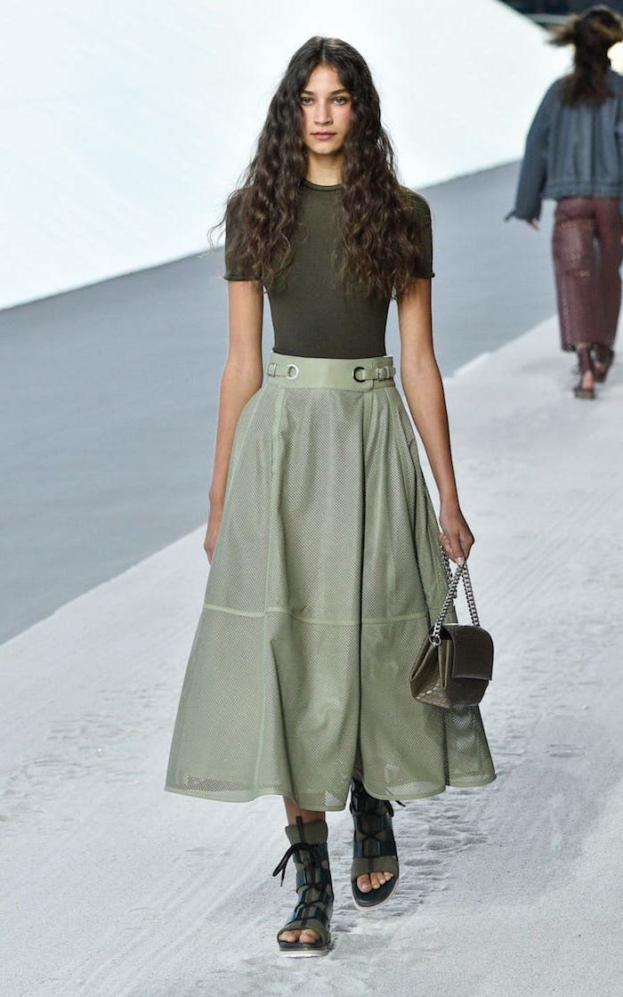 model with long curly black hair, winter fashion for women, wearing green skirt and blouse, green open toe sandals