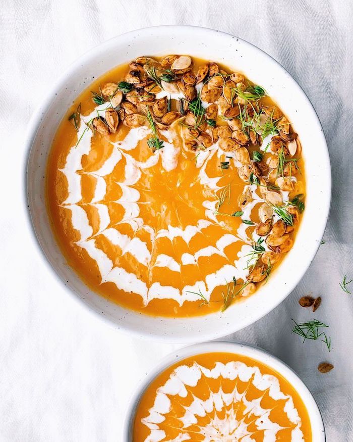 white ceramic bowl full of soup, nuts on top for garnish, creamy tortellini soup, white table cloth