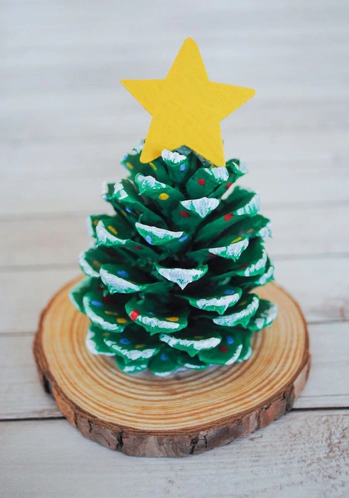pinecone painted in green, placed on small wooden log, christmas arts and crafts, step by step diy tutorial