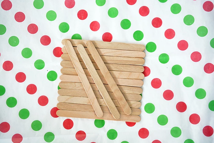 popsicle sticks, placed on white sheet with red and green dots, christmas crafts for kids, step by step diy tutorial