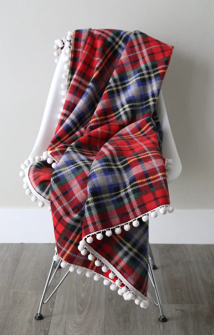 red flannel fleece blanket, spread out on white chair, placed on a wooden floor, christmas presents for moms