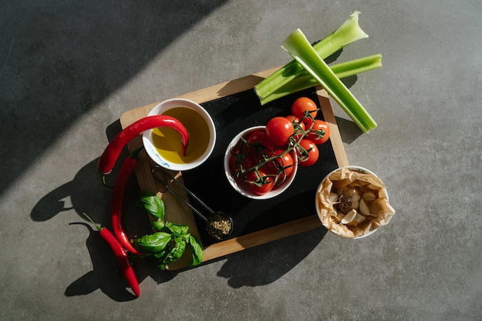 chilli peppers and tomatoes, celery and garlic, arranged on wooden cutting board, tomato soup, grey countertop