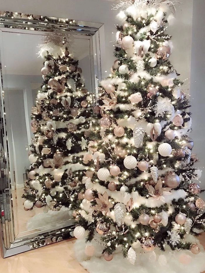 white garland wrapped around a tree, rose gold and white ornaments, elegant christmas tree decorating ideas, placed in front of a mirror on white rug