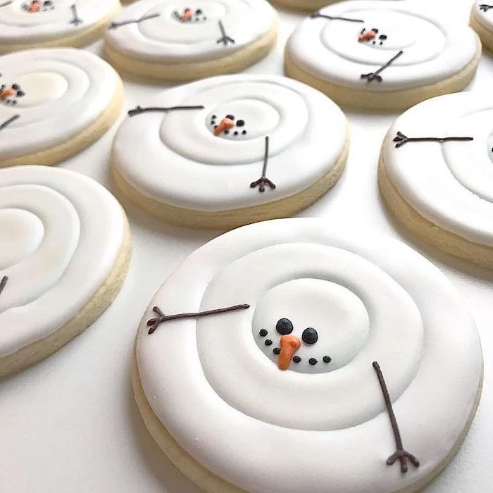 royal icing christmas cookies, round cookies with marshmallow fluff on top, shaped as snowmen, placed on white surface