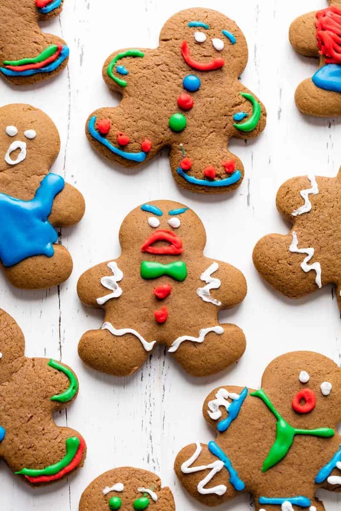 gingerbread men with different faces, colorful icing on top, cookie icing, placed on white wooden surface
