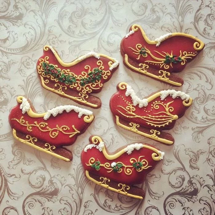 santa's sled shaped cookies, decorated with red green white and gold icing, royal icing christmas cookies, placed on white surface