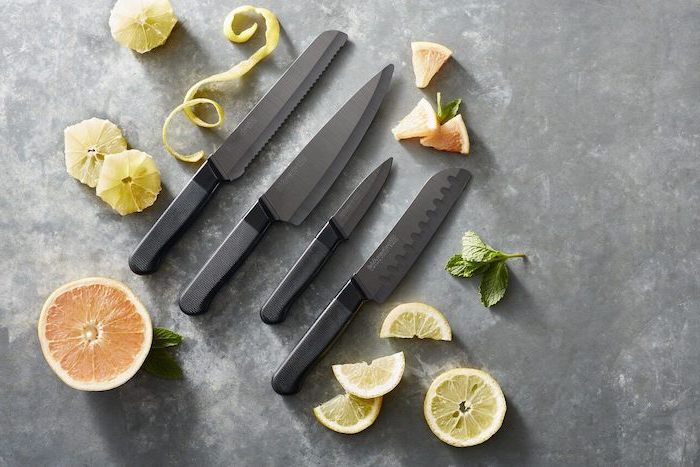 gifts for mom from son, a set of four black knives, placed on granite countertop, sliced fruits around them