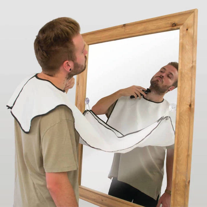man wearing grey t shirt, shaving apron attached to a mirror, creative gifts for boyfriend, mounted on white wall